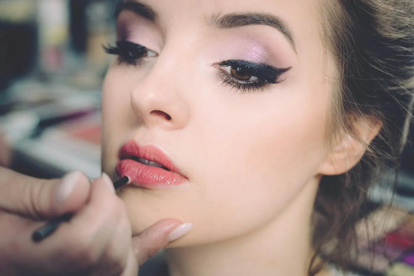 Makeup artist applying lipstick to a client in a beauty salon